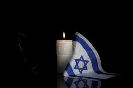 Téléchargez les photos : Bougie ardente avec drapeau d'Israël et fil de fer barbelé sur fond sombre. Journée internationale de commémoration de l'Holocauste - en image libre de droit