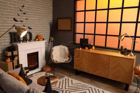 Photo for Interior of festive living room with fireplace, wooden cabinet, armchair and Halloween decorations - Royalty Free Image