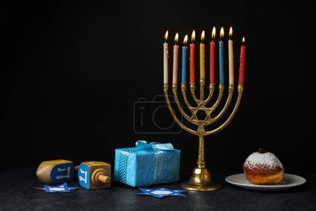 Menorah with candles, dreidels and gift box for Hanukkah on black background-stock-photo