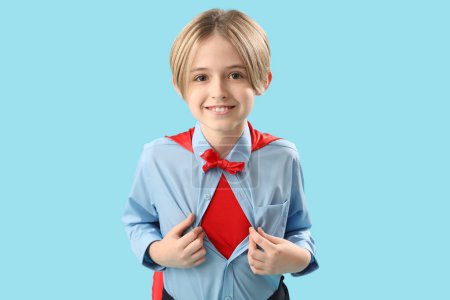 Téléchargez les photos : Petit acteur habillé en super héros sur fond bleu - en image libre de droit