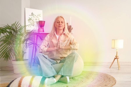Foto de Meditar mujer madura con aura colorida en casa - Imagen libre de derechos