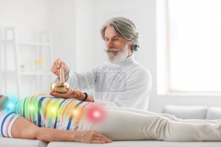 Photo for Male Reiki master with Tibetan singing bowl healing patient - Royalty Free Image