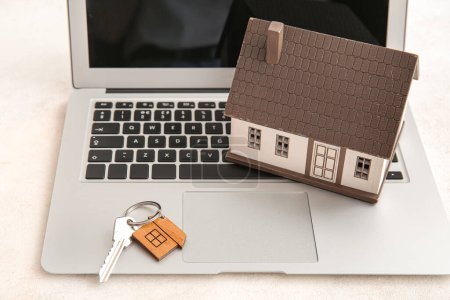 Téléchargez les photos : Figure de la maison avec clé, bibelot et ordinateur portable sur fond blanc grunge. Concept d'achat immobilier - en image libre de droit