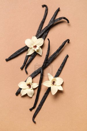 Aromatic vanilla sticks and flowers on brown background