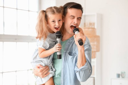 Téléchargez les photos : Petite fille mignonne et son père avec des micros chantant à la maison - en image libre de droit