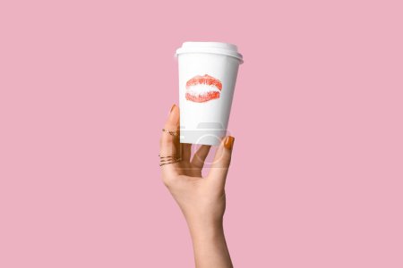 Photo for Female hand with red manicure holding paper cup of coffee on pink background - Royalty Free Image