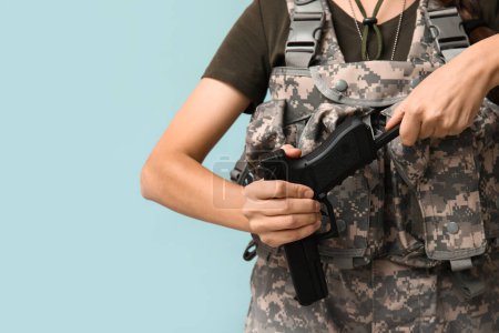 Photo for Female soldier reloading handgun on blue background, closeup - Royalty Free Image