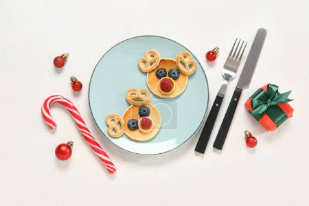 Photo for Plate with pancakes in shape of reindeers on white background. Christmas celebration - Royalty Free Image