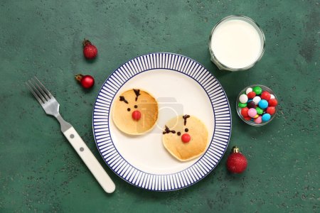Photo for Plate with pancakes in shape of reindeers on green table. Christmas celebration - Royalty Free Image