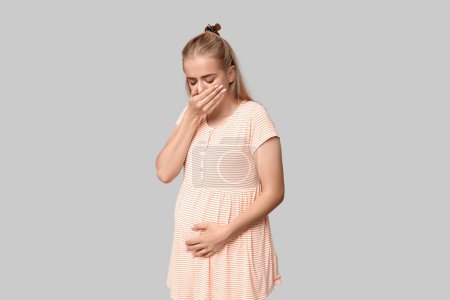 Téléchargez les photos : Belle jeune femme enceinte souffrant de toxicose sur fond gris - en image libre de droit