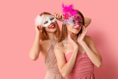 Téléchargez les photos : Belles jeunes femmes en masques de carnaval sur fond rose - en image libre de droit