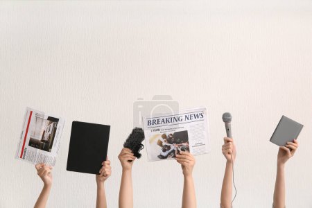 Téléchargez les photos : Mains féminines avec journaux, micros et cahiers sur fond clair - en image libre de droit