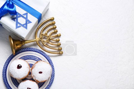 Photo for Plate with tasty donuts, gift box and menorah for Hanukkah celebration on light background - Royalty Free Image