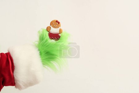 Photo for Green hairy hand of creature in Santa costume with Christmas gingerbread cookies on white background - Royalty Free Image