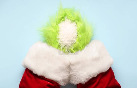 Foto de Verde manos peludas de criatura en traje de Santa con nieve decorativa sobre fondo azul - Imagen libre de derechos