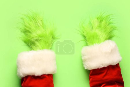 Photo for Green hairy hands of creature in Santa costume on green background - Royalty Free Image