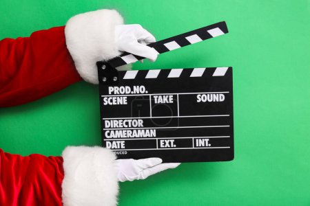 Photo for Santa hands with movie clipper on green background - Royalty Free Image