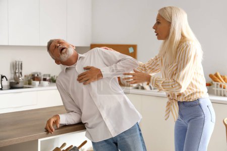 Photo for Mature woman and her husband having heart attack in kitchen - Royalty Free Image