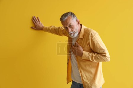 Photo for Mature man having heart attack on yellow background - Royalty Free Image