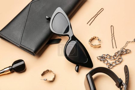 Foto de Composición con elegantes gafas de sol, reloj inteligente moderno y accesorios femeninos sobre fondo beige, primer plano - Imagen libre de derechos