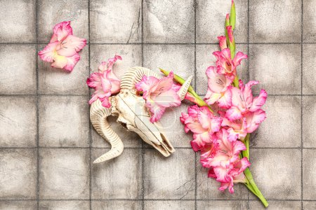 Téléchargez les photos : Crâne de mouton avec de belles fleurs de lys sur fond de tuiles grises - en image libre de droit