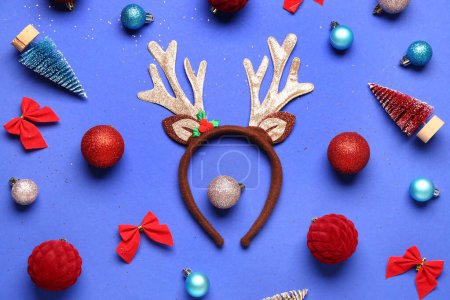 Téléchargez les photos : Mignonnes cornes de rennes avec décorations de Noël sur fond bleu - en image libre de droit
