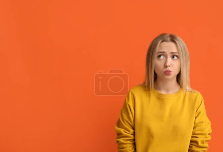 Photo for Embarrassed young woman on orange background - Royalty Free Image