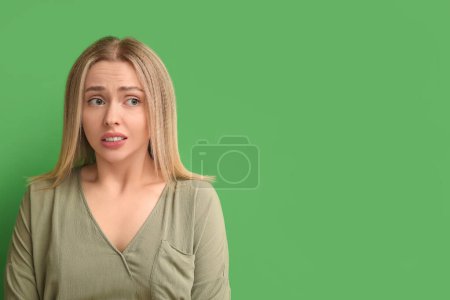 Photo for Young woman feeling embarrassment on green background - Royalty Free Image