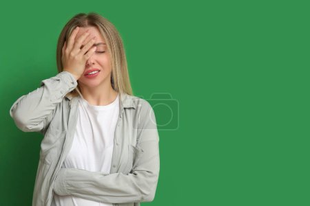 Photo for Young woman doing facepalm on green background - Royalty Free Image