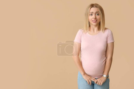 Photo for Young pregnant woman feeling shame on beige background - Royalty Free Image
