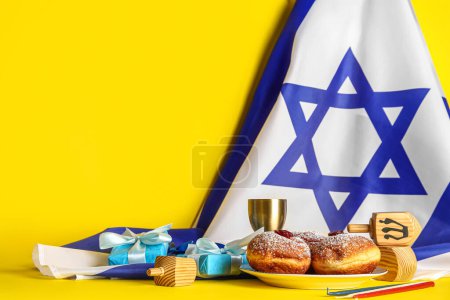 Photo for Israel flag with tasty donuts, gift boxes, dreidels and cup on yellow background. Hanukkah celebration - Royalty Free Image
