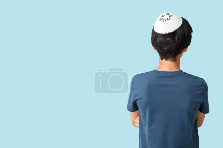 Little Israeli boy in kipa on blue background, back view