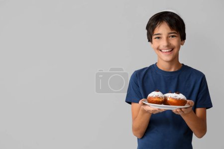 Photo for Little boy in kipa holding plate with tasty donuts on grey background. Hanukkah celebration - Royalty Free Image