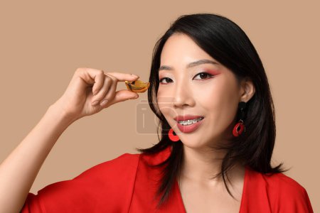 Photo for Beautiful young happy Asian woman with boat on brown background. Chinese New Year celebration - Royalty Free Image