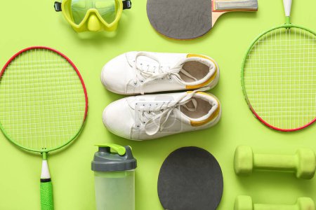 Photo for Different sports equipment and sneakers on green background - Royalty Free Image