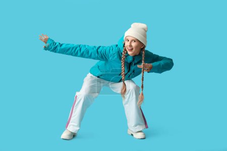 Photo for Beautiful young happy woman in warm winter clothes on blue background - Royalty Free Image