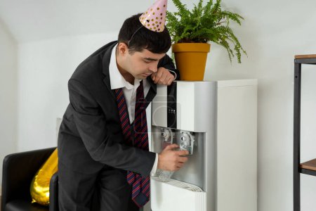 Foto de Resaca hombre de negocios vertiendo agua del refrigerador después de la fiesta de Año Nuevo en la oficina - Imagen libre de derechos