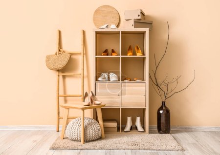 Shelving unit with different stylish shoes, ladder and stool near beige wall in boutique