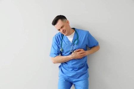 Photo for Male doctor having heart attack on light background - Royalty Free Image