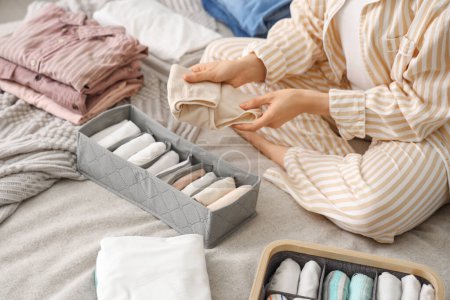 Woman sorting clothes on bed in bedroom, closeup