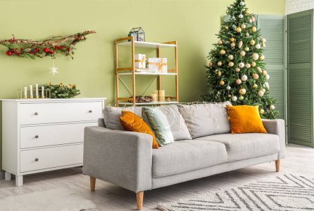 Stylish interior of modern living room with comfortable sofa and Christmas tree