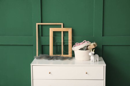 Photo for Empty picture frames and beautiful Christmas decor on chest of drawers against color wall - Royalty Free Image