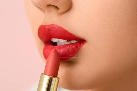 Téléchargez les photos : Belle jeune femme appliquant du rouge à lèvres sur fond rose, gros plan - en image libre de droit