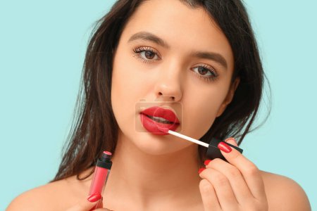 Téléchargez les photos : Belle jeune femme avec du rouge à lèvres liquide sur fond de couleur, gros plan - en image libre de droit