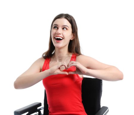 Foto de Mujer joven en silla de ruedas haciendo gesto de corazón sobre fondo blanco - Imagen libre de derechos
