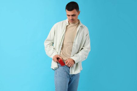 Téléchargez les photos : Jeune homme avec cigarette électronique sur fond bleu - en image libre de droit
