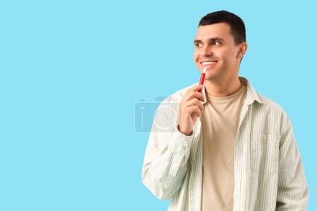 Téléchargez les photos : Jeune homme fumant cigarette électronique sur fond bleu - en image libre de droit