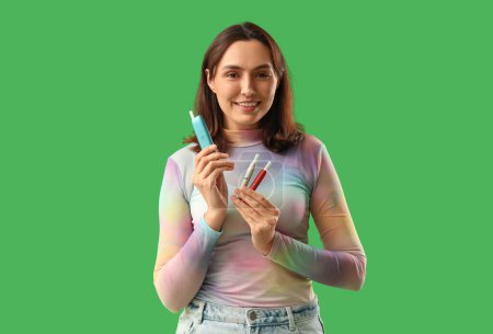 Téléchargez les photos : Jeune femme avec des cigares électroniques sur fond vert - en image libre de droit