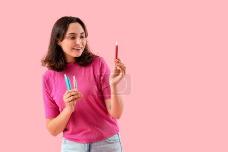 Téléchargez les photos : Jeune femme avec des cigares électroniques sur fond rose - en image libre de droit