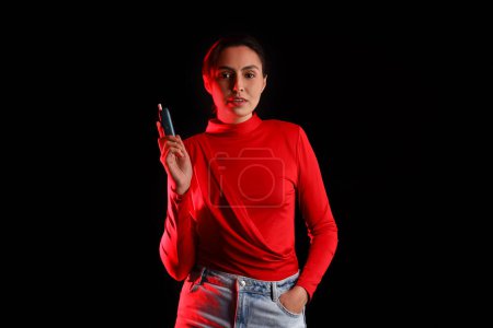 Téléchargez les photos : Jeune femme avec cigare électronique sur fond sombre - en image libre de droit